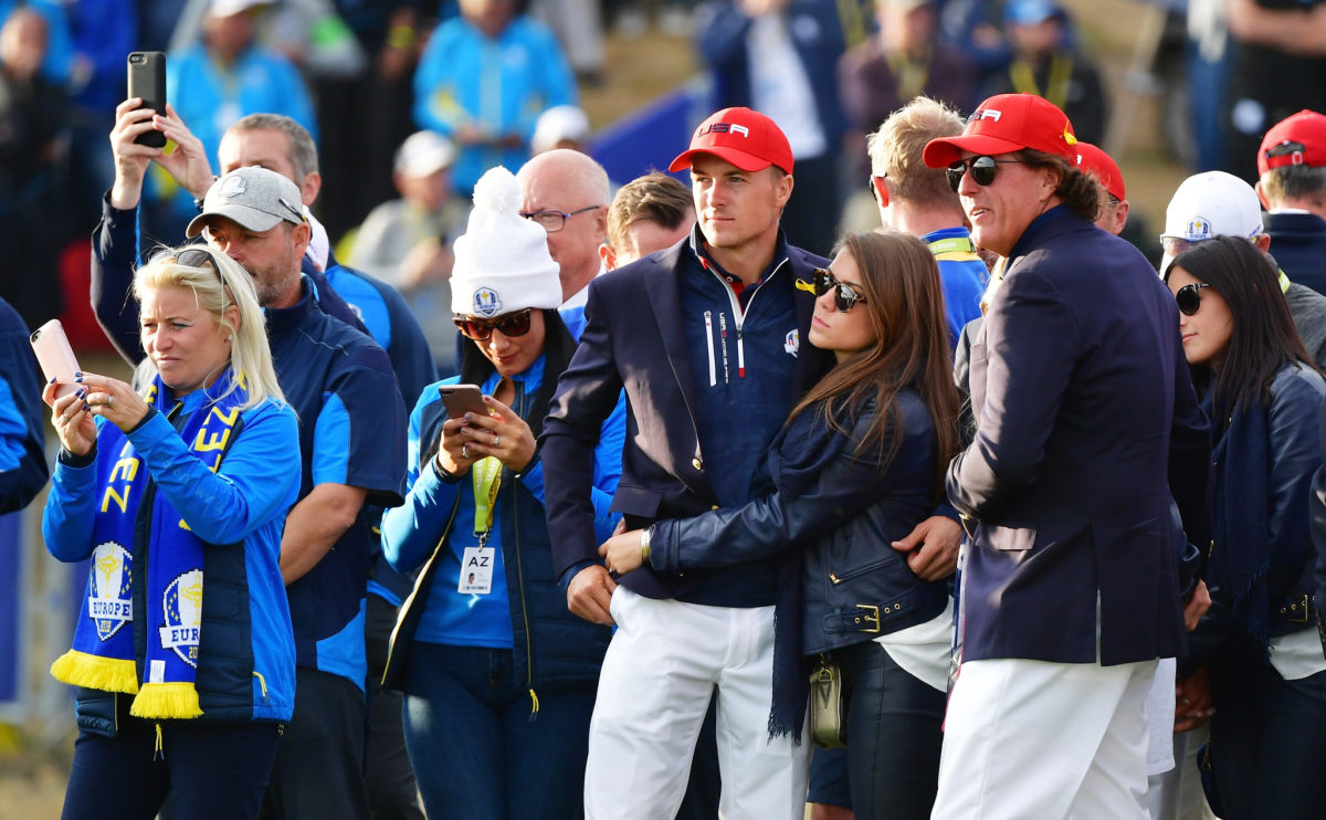 Jordan Spieth standing with his wife on the golf course.