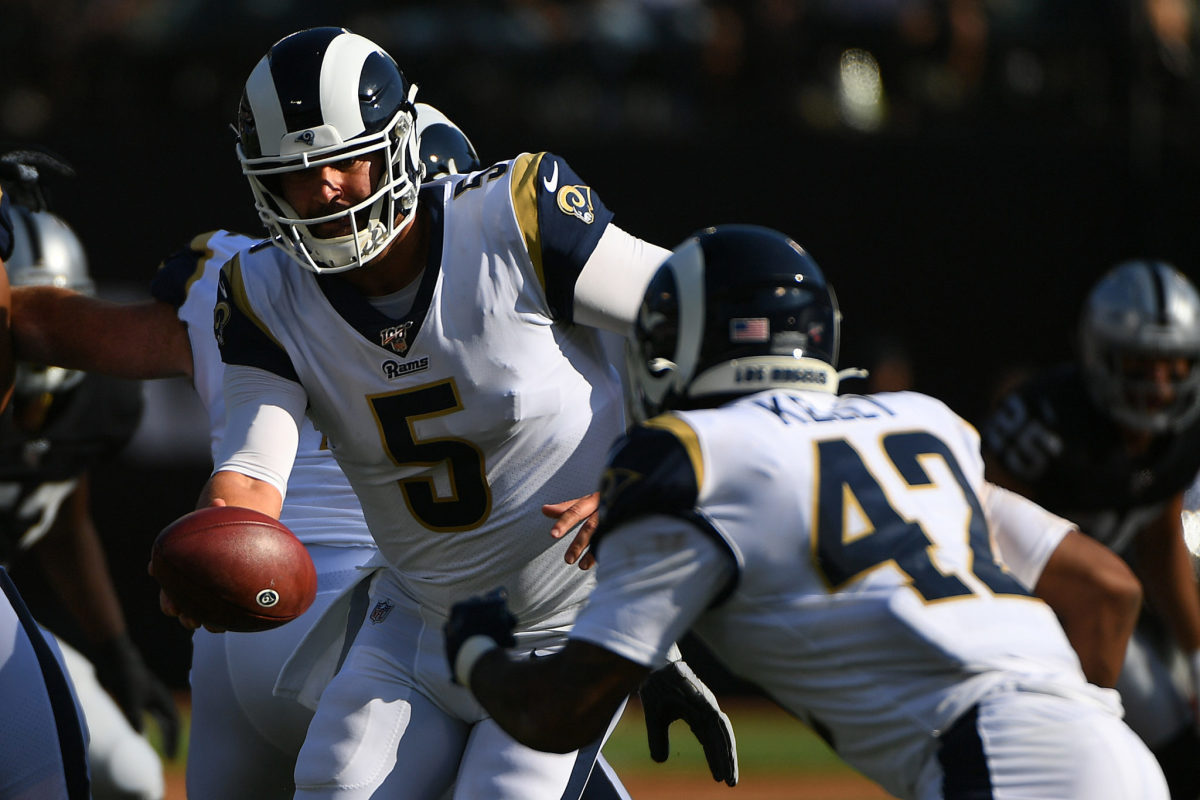 Rams quarterback Blake Bortles hands the ball to a running back.