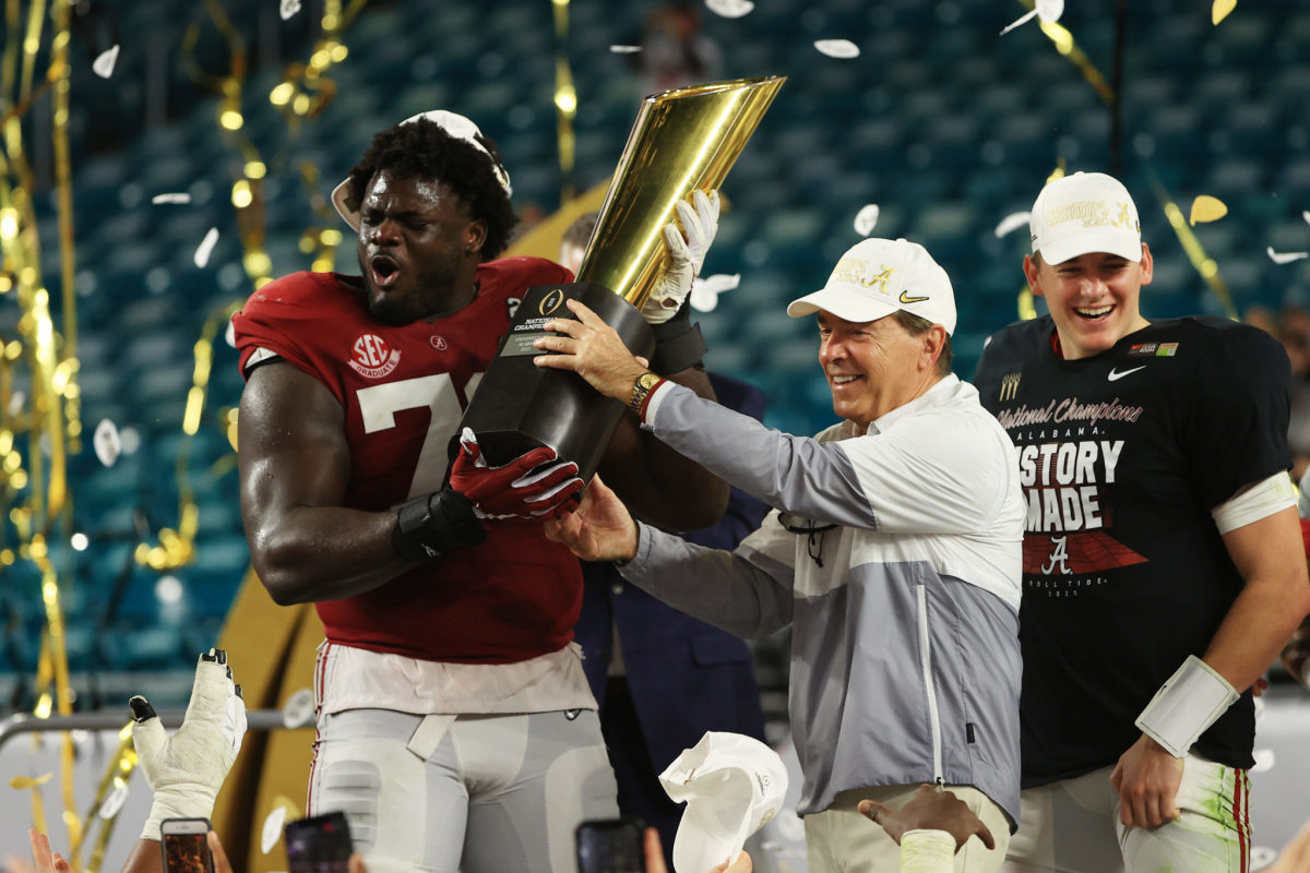 Nick Saban and Alex Leatherwood lift the national title trophy.