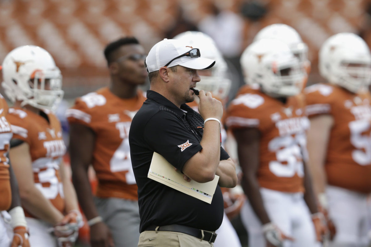 Texas Longhorns coach Tom Herman holding a whistle in his mouth.