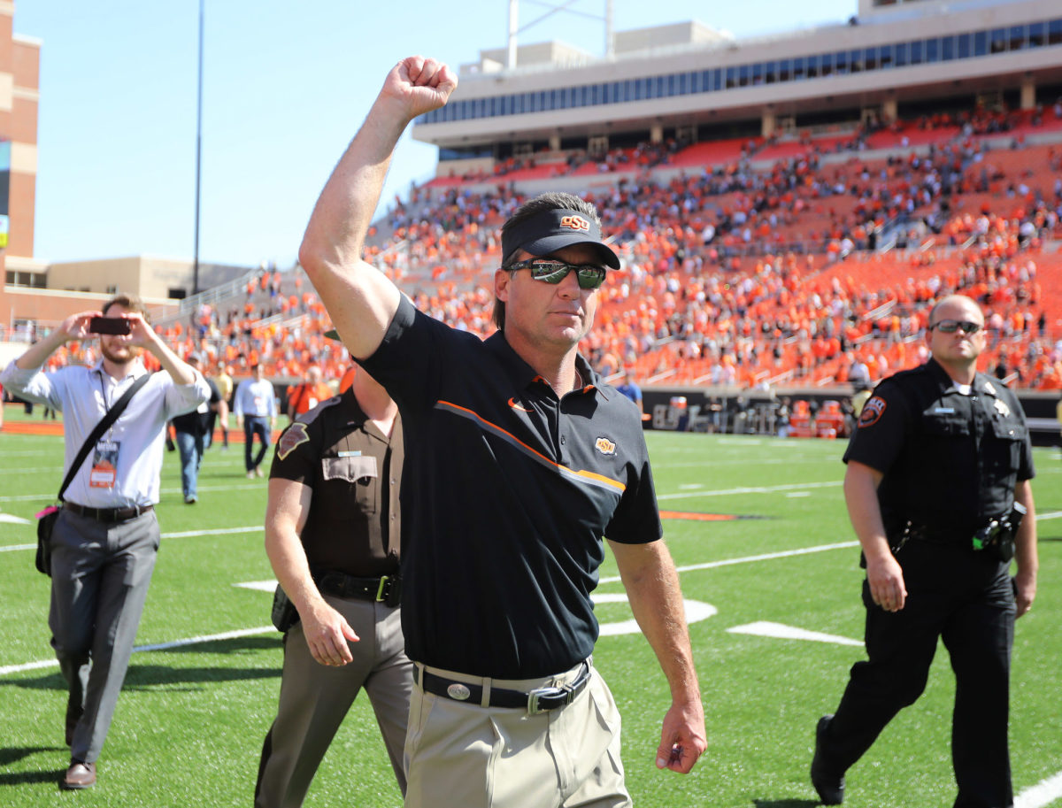 Mike Gundy raises his hand while walking off after beating Texas.