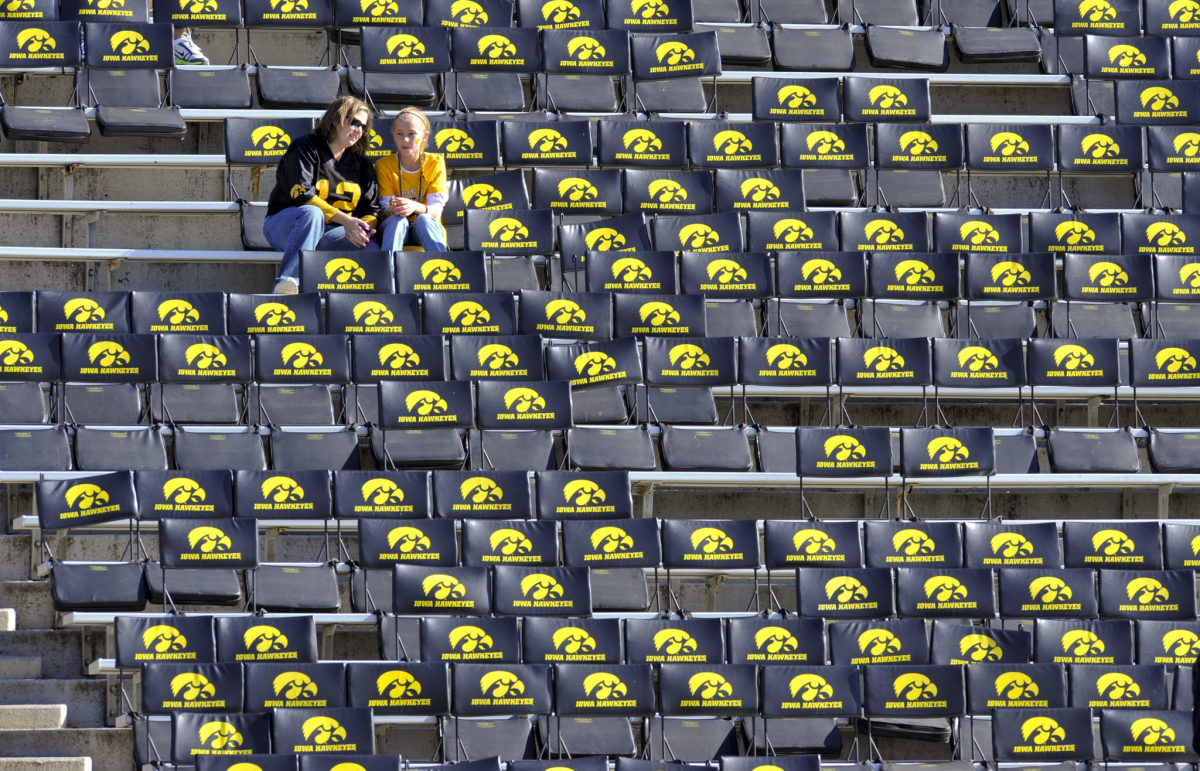 Two Iowa fans sitting in the stands before a football game.