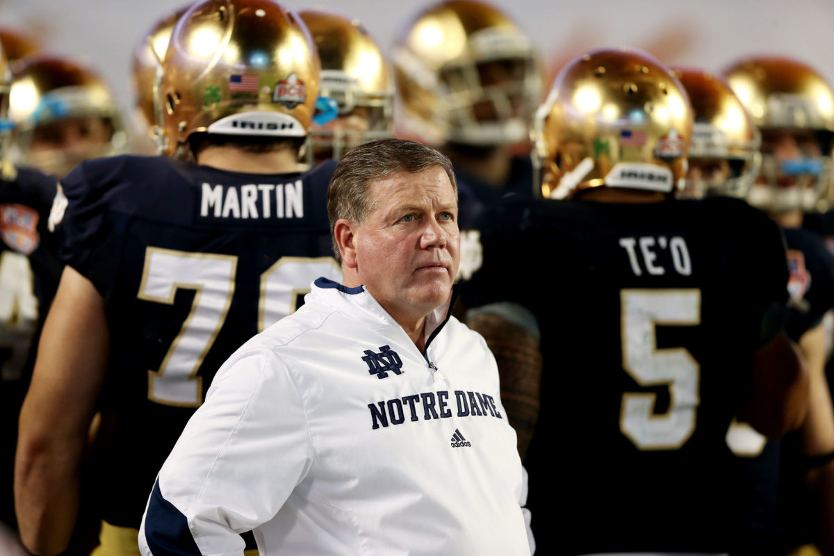 Brian Kelly standing with his Notre Dame football players.