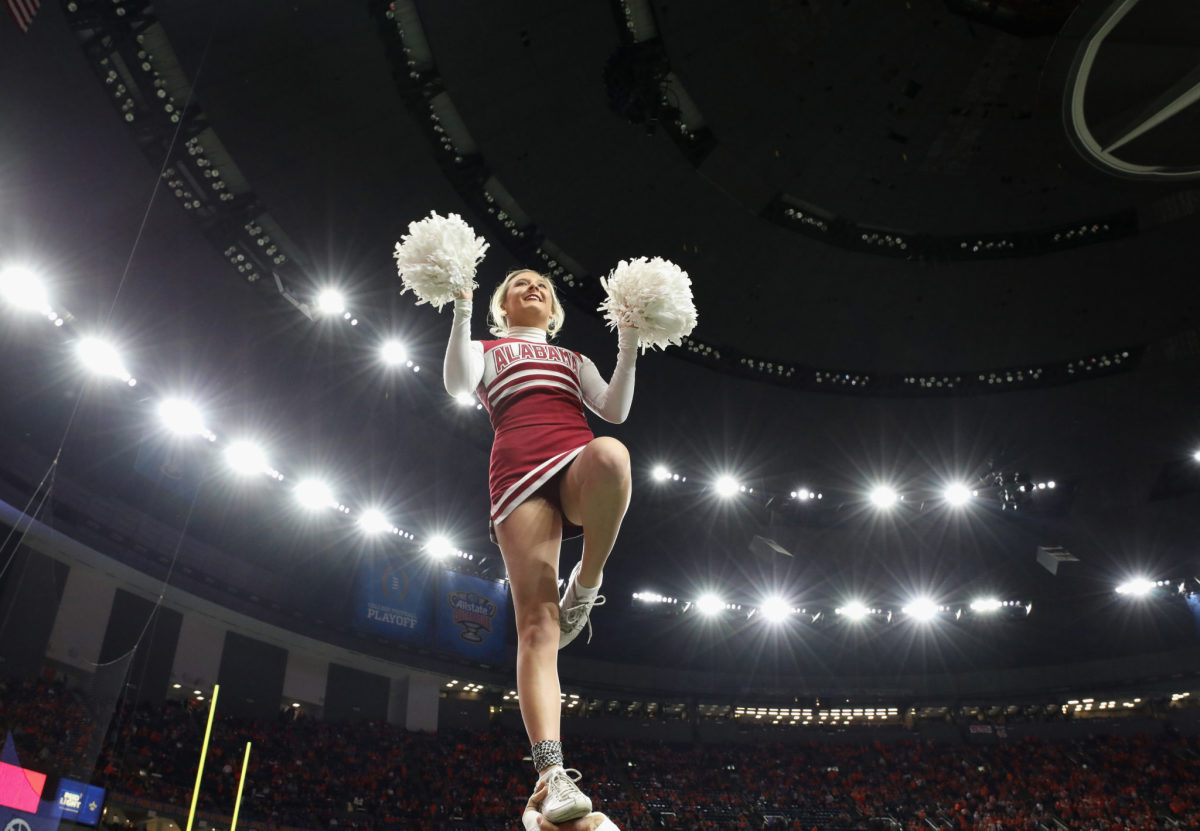 an alabama cheerleader on the field at the college football playoff
