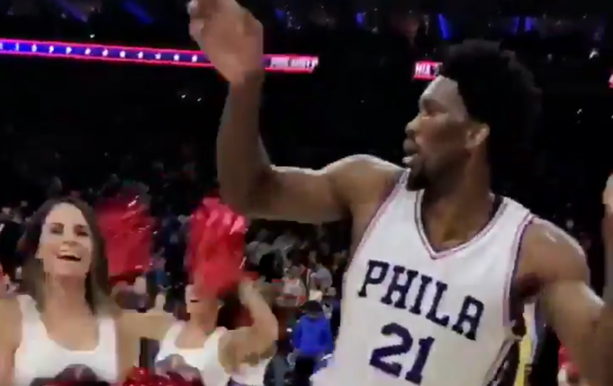 Joel Embiid excited with a fan in the background.