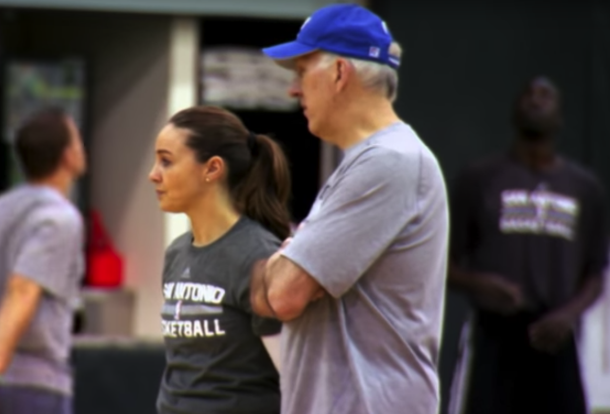 Becky Hammon and Gregg Popovich talking while coaching the Spurs.