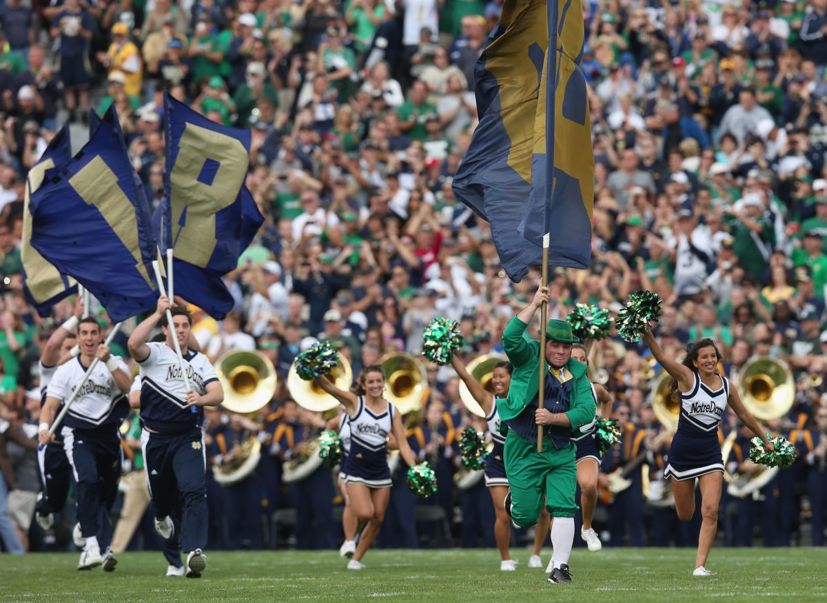 Notre Dame's mascot running on the field with a flag.