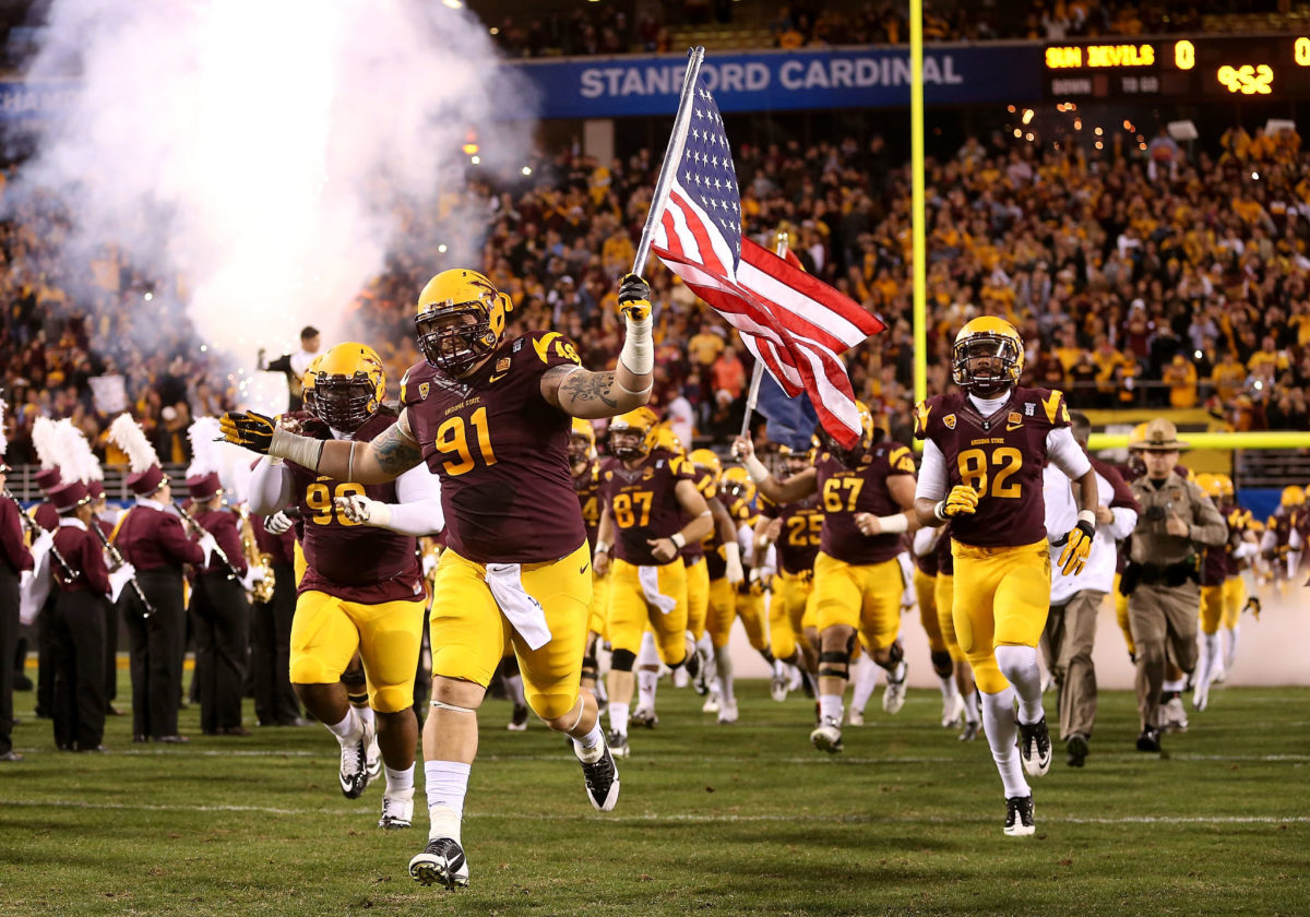 Defensive tackle Jake Sheffield #91 of the Arizona State Sun Devils carries an American Flag as he leads teamamtes out onto the field before the Pac 12 Championship game against the Stanford Cardinal at Sun Devil Stadium.