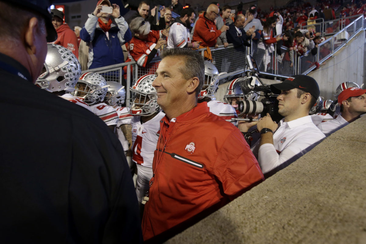 Urban Meyer walking onto the field with his Ohio State football players