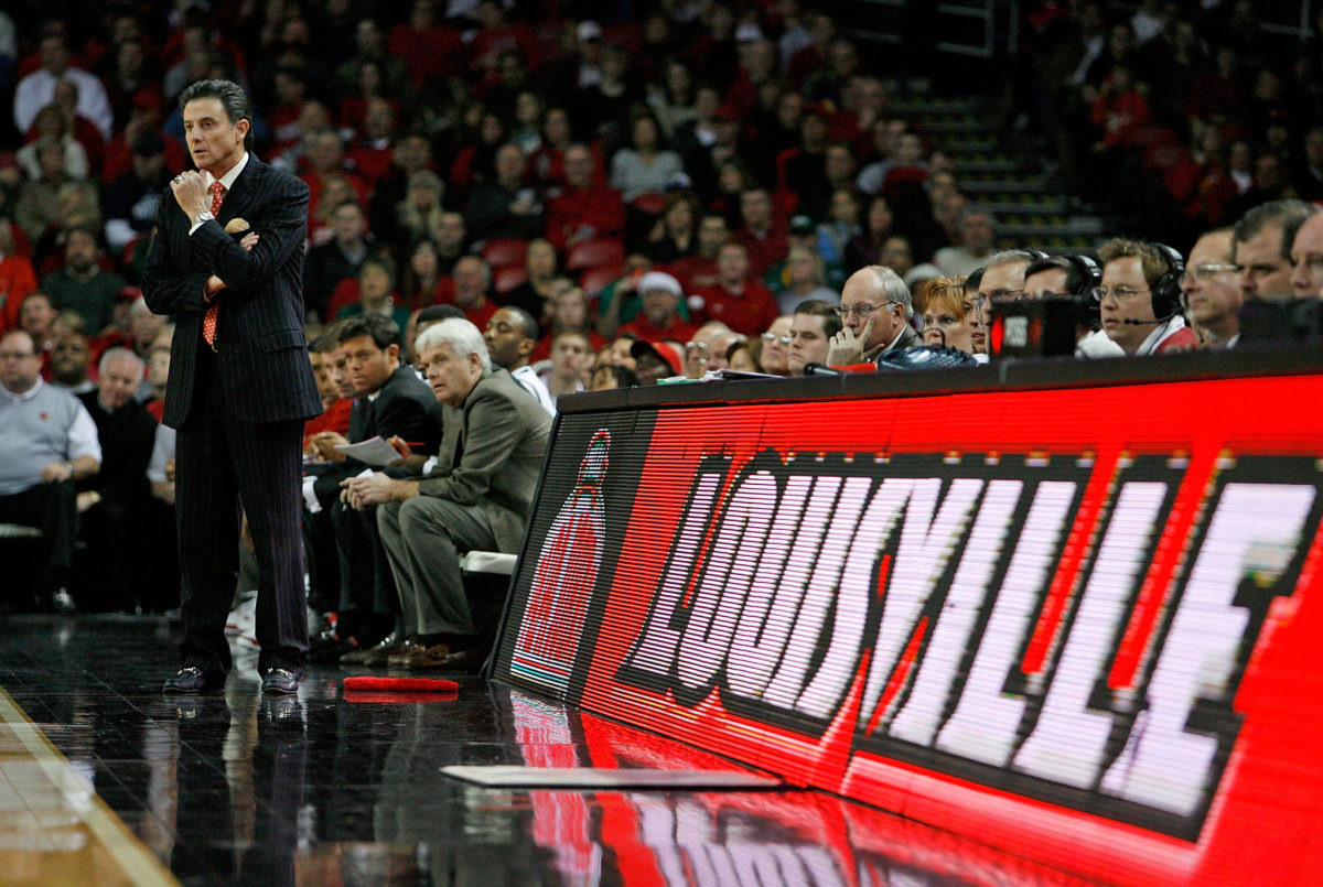 Rick Pitino coaching in front of a Louisville sign.