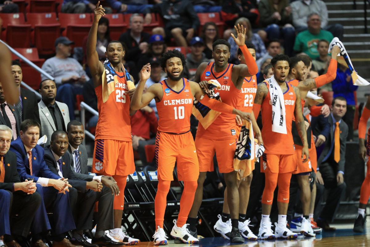 Aamir Simms #25, Gabe DeVoe #10, Elijah Thomas #14, Shelton Mitchell #4, Marcquise Reed #2, David Skara #24 and Anthony Oliver II #21 of the Clemson Tigers celebrate on the bench as they defeat the Auburn Tigers.