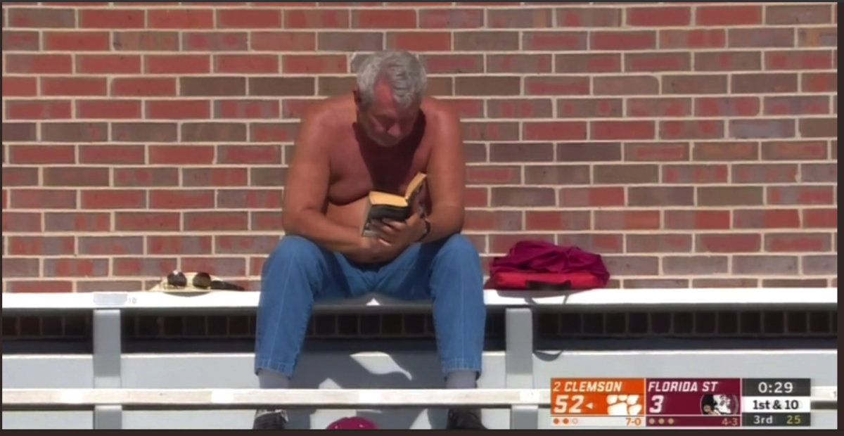 A shirtless Florida State fans reads a book at the end of the Clemson loss.