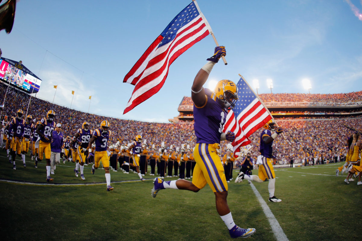 An LSU player carries the American flag onto the field.
