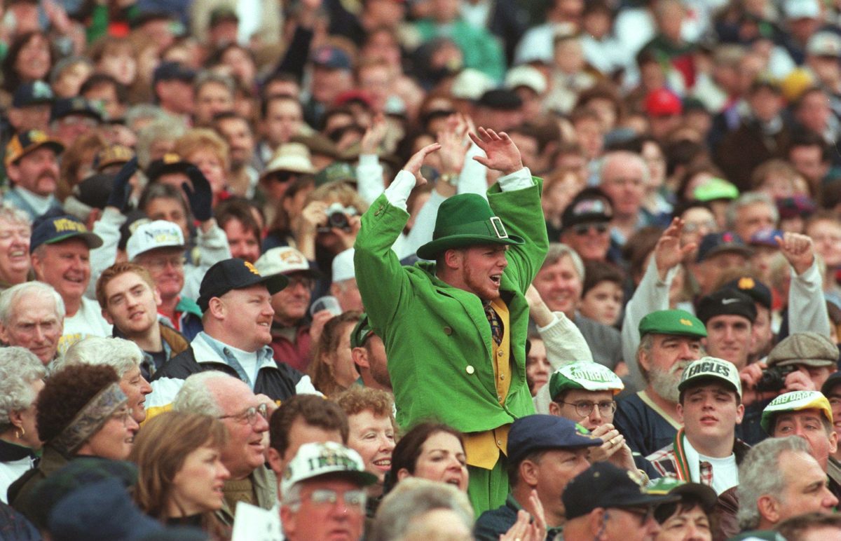 A fan sitting in the stands dressed as Notre Dame's mascot.