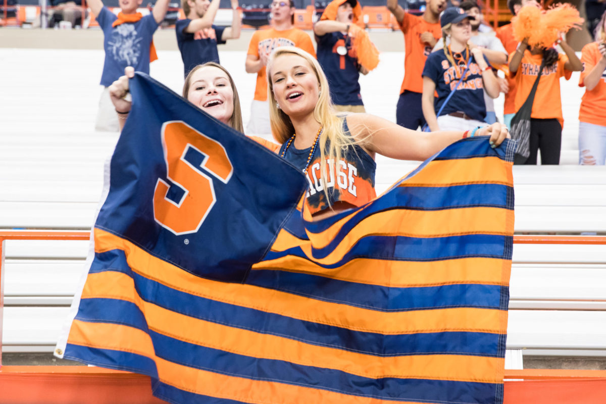 Two female fans holding up a Syracuse flag.