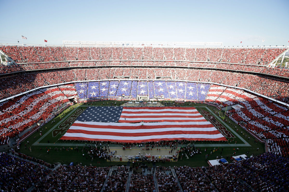 A general view of the San Francisco 49ers field with an American flag stretched across it.