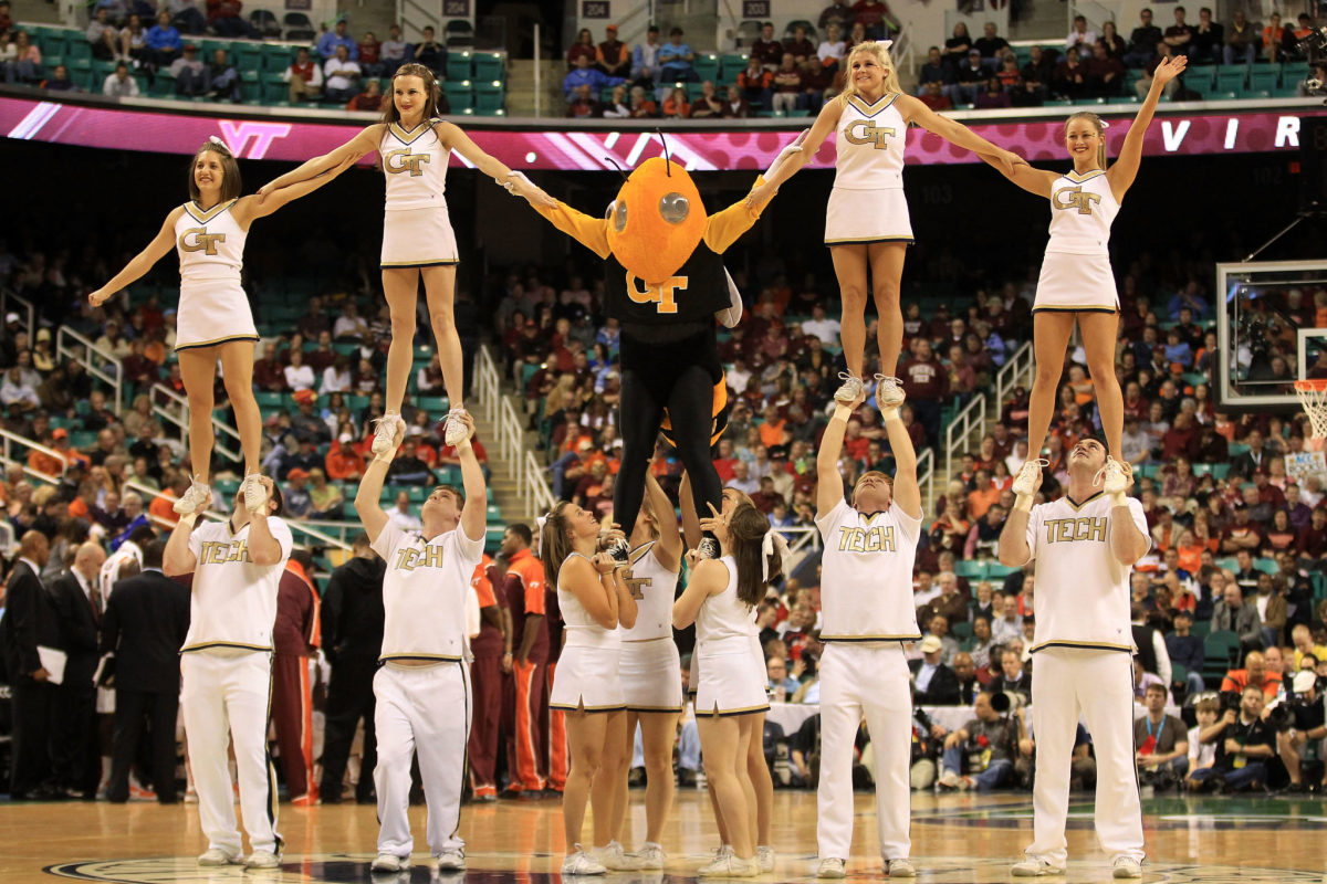 Georgia Tech's cheerleaders holding up the team's mascot.