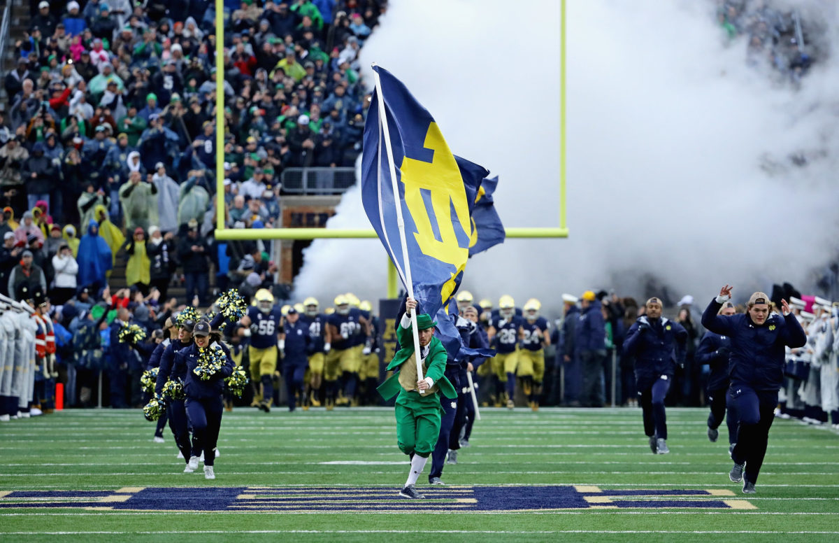 Notre Dame's mascot leading the football team onto the field.