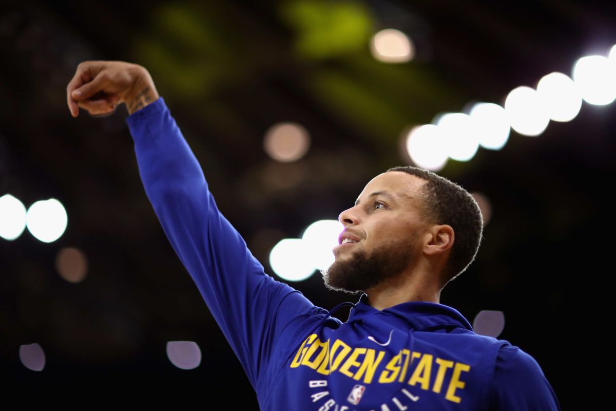 Steph Curry warming up in a Golden State Warriors hoodie.