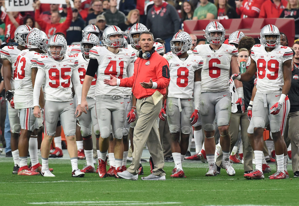 Urban Meyer standing with his Ohio State football team during a stop in play.
