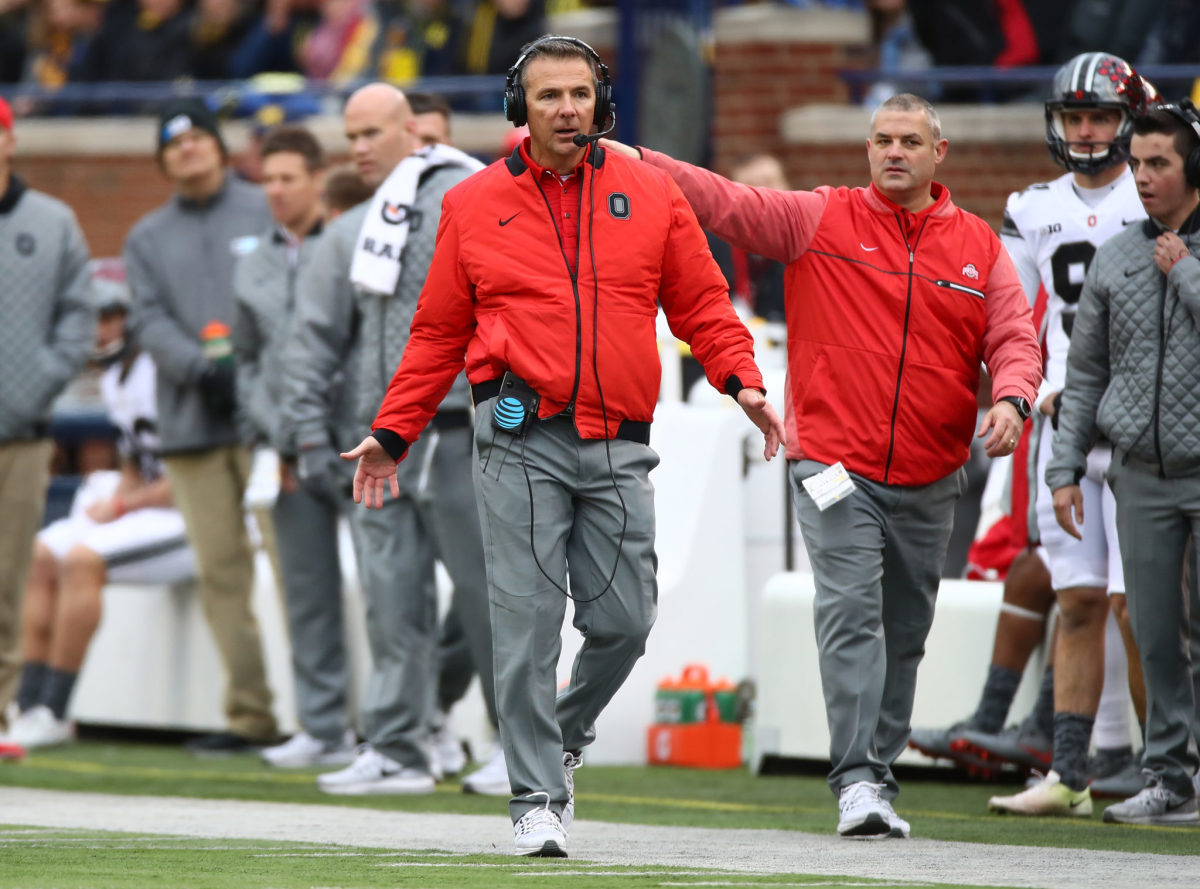 Urban Meyer walking down the sideline in an Ohio State jacket.