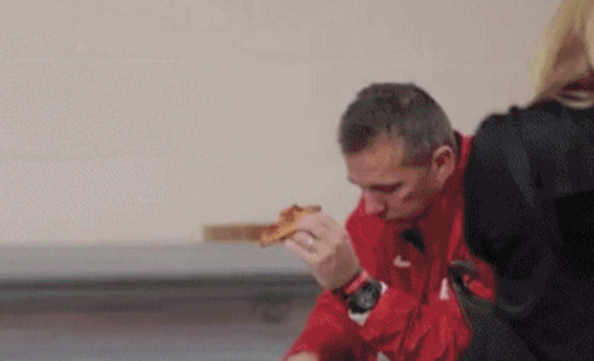 Urban Meyer eating a slice of pizza.