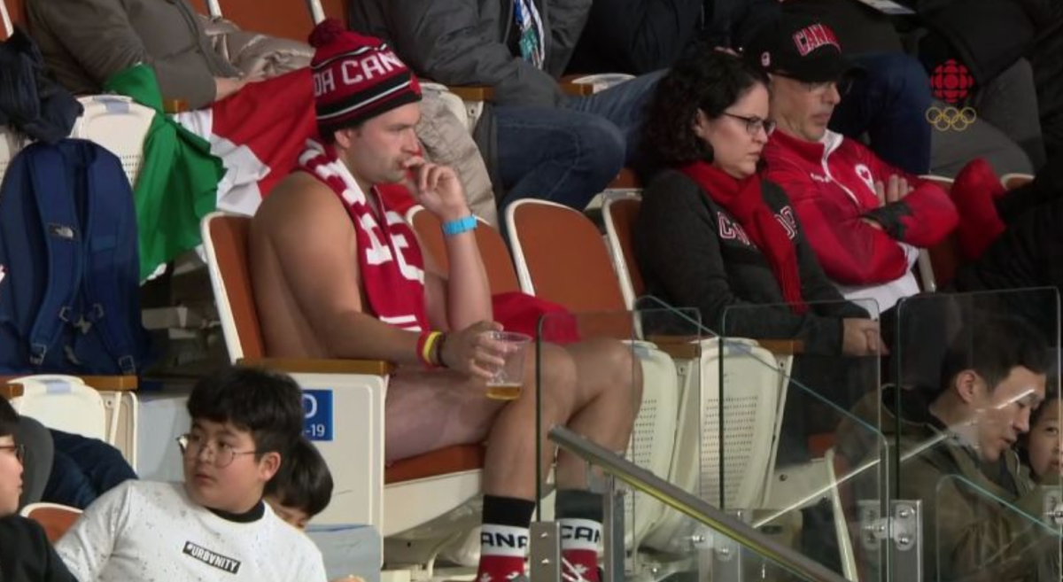 A naked Canadian fan sits in the crowd.