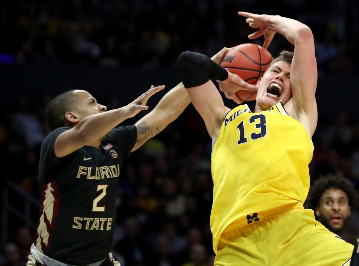 Moe Wagner of the Michigan Wolverines is fouled by CJ Walker #2 of the Florida State Seminoles.