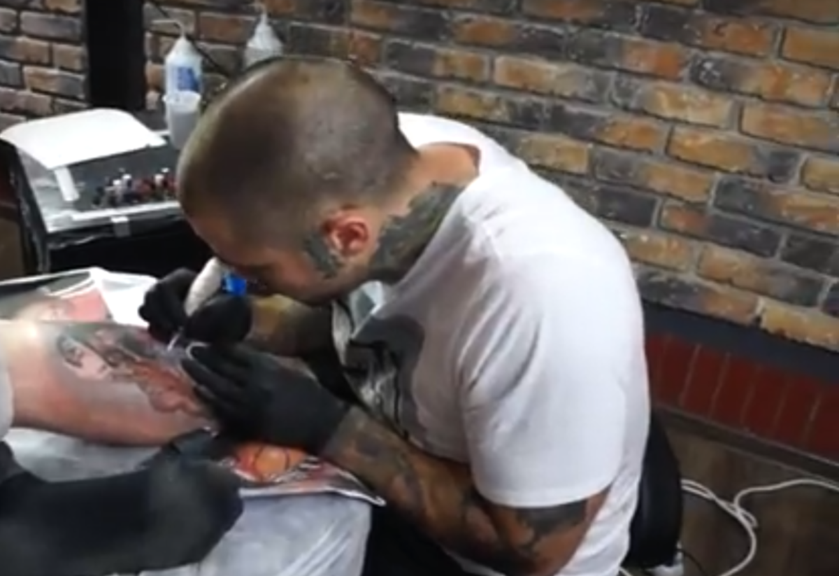 Steve Butcher tattoos a man's leg.