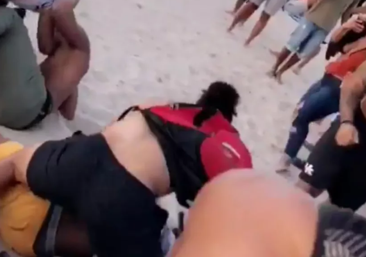 College football players fight on the beach.