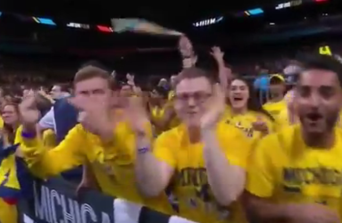 A Michigan fan flips two middle fingers at the camera.