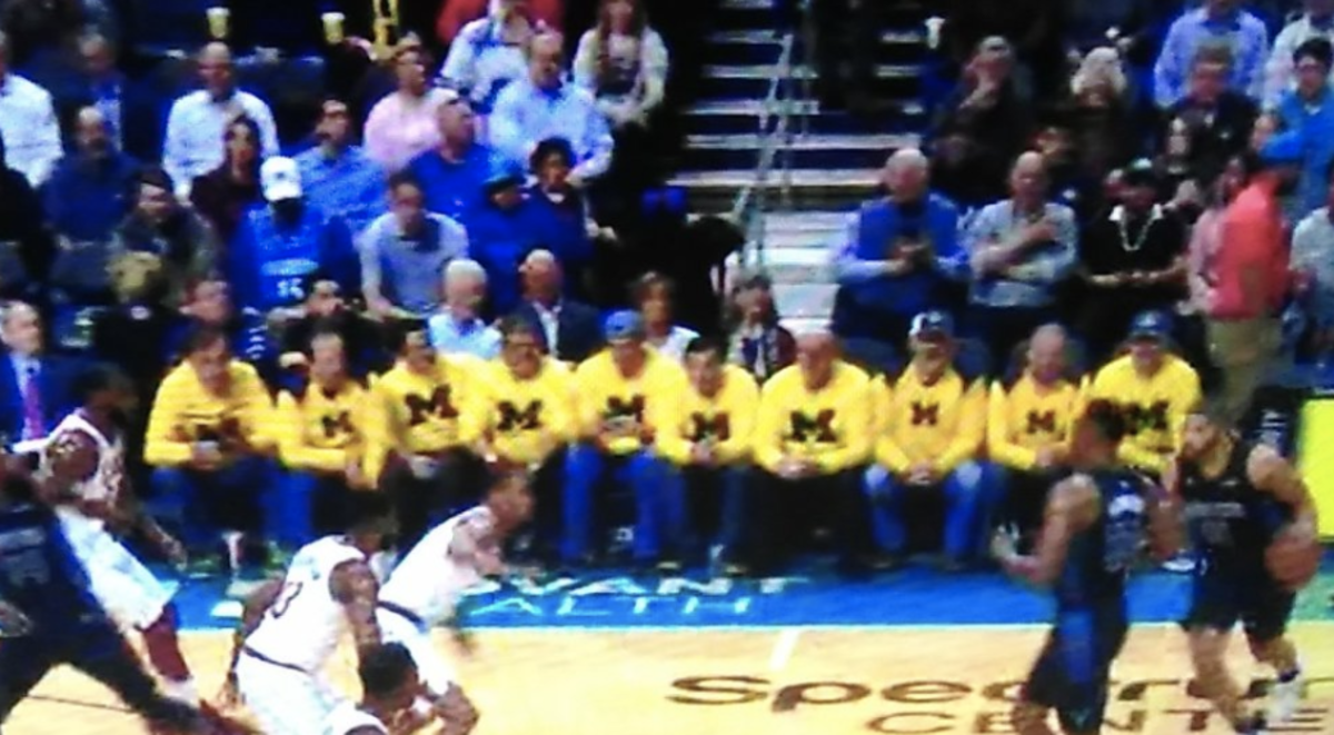 Michigan fans sit courtside at an NBA game.