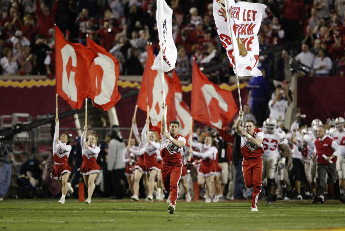 Ohio State cheerleaders leading the football team onto the field.