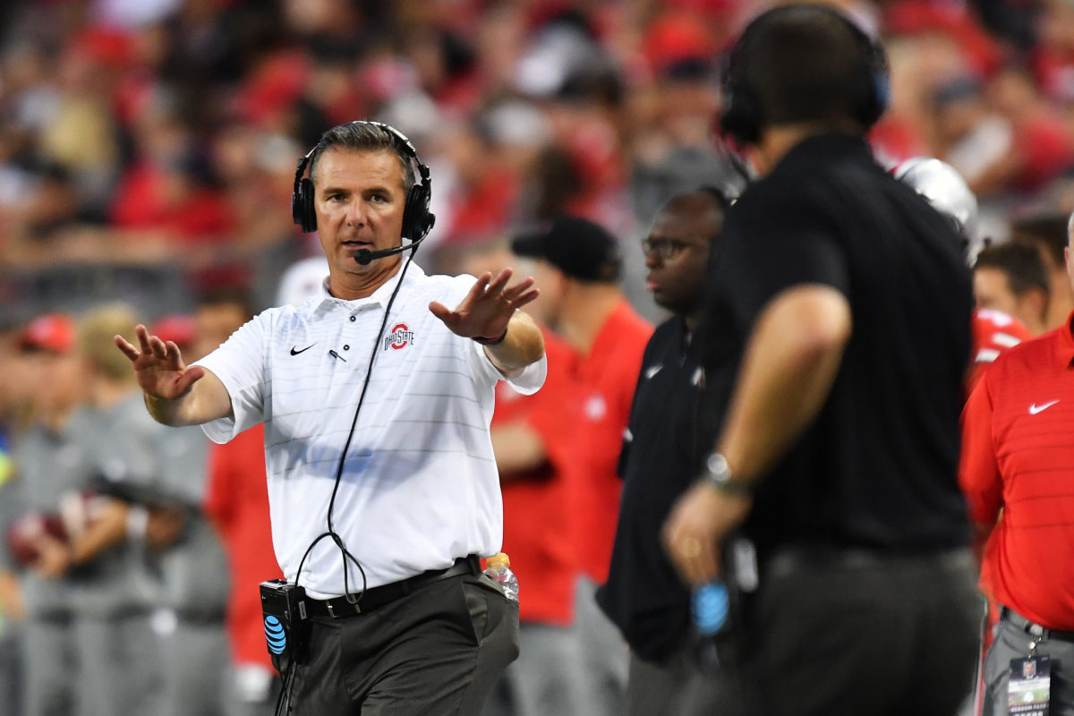 urban Meyer talking to his coaches on the sideline during an Ohio State football game.