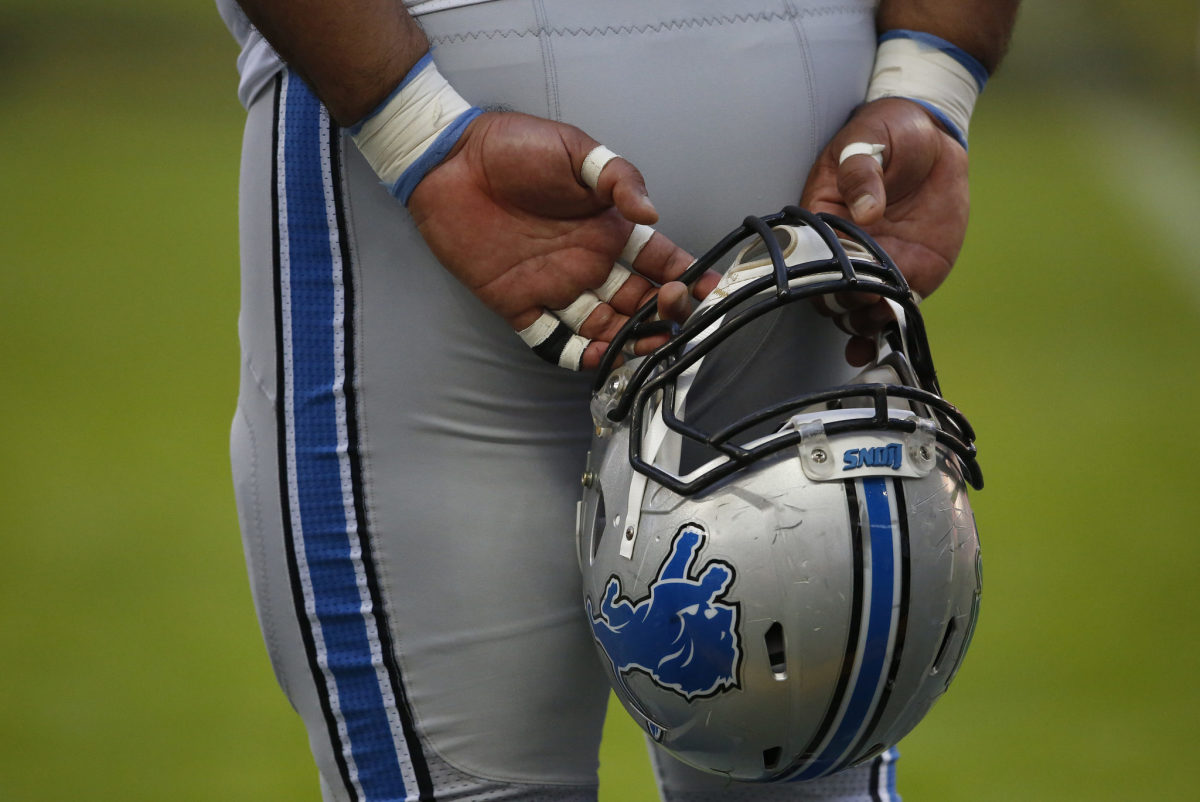 A Detroit Lions player holding his helmet behind his back before a game.