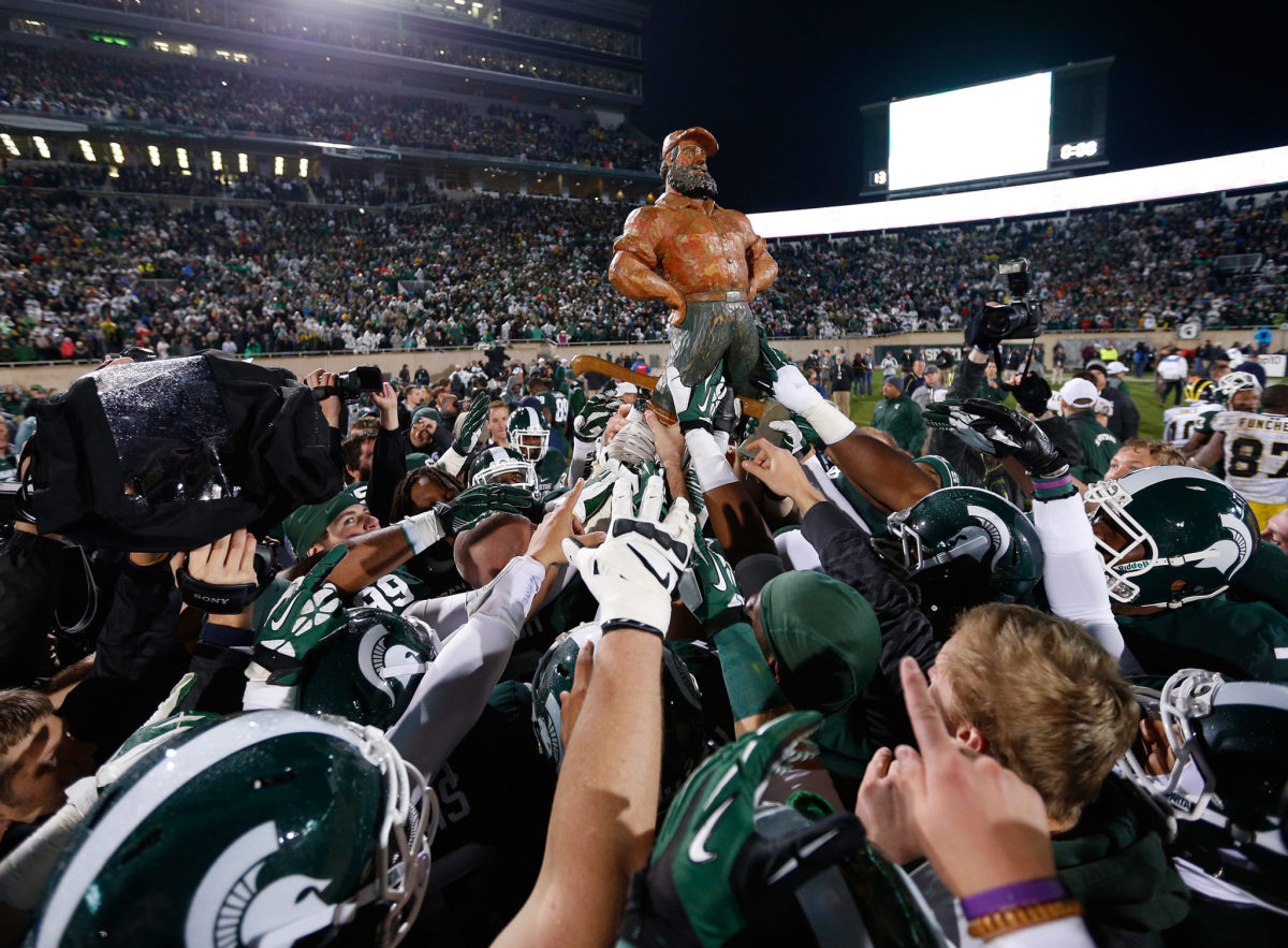 Michigan State Spartans carry off the Paul Bunyan Trophy as they celebrate their 29-6 win over the Michigan Wolverines.
