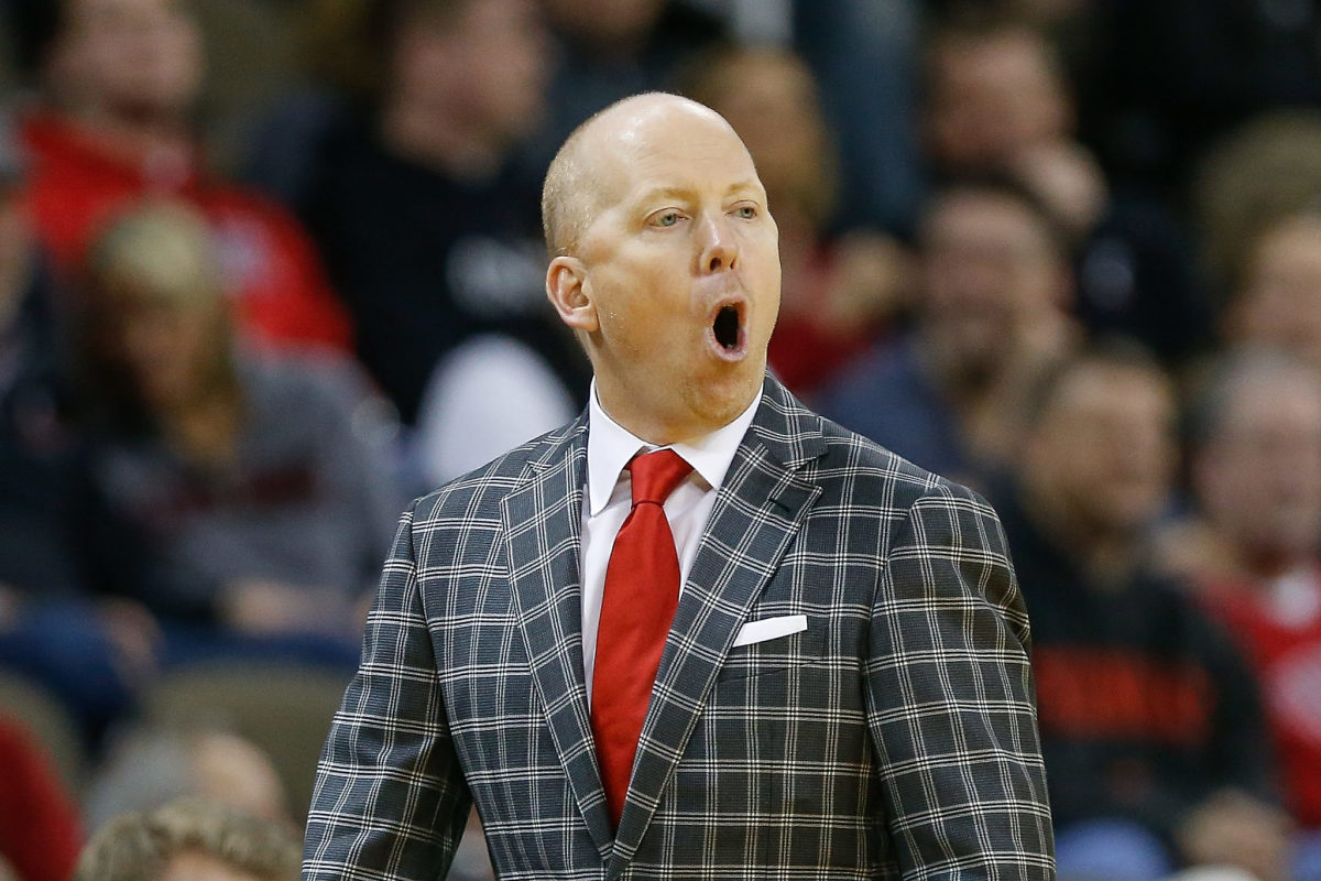 Mick Cronin with his mouth wide open while wearing a red tie.
