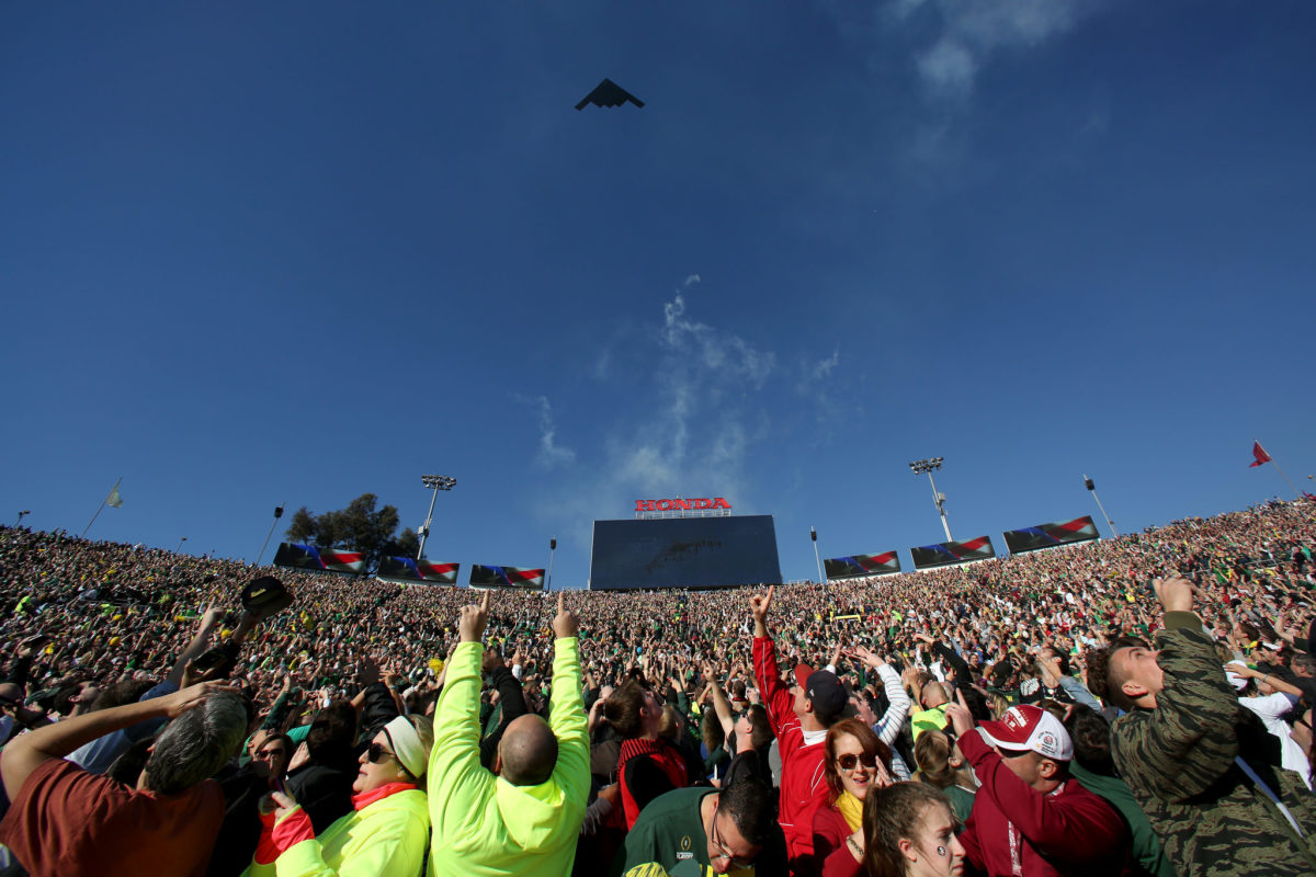 Fans point at a B-2 flyover before the Rose Bowl.