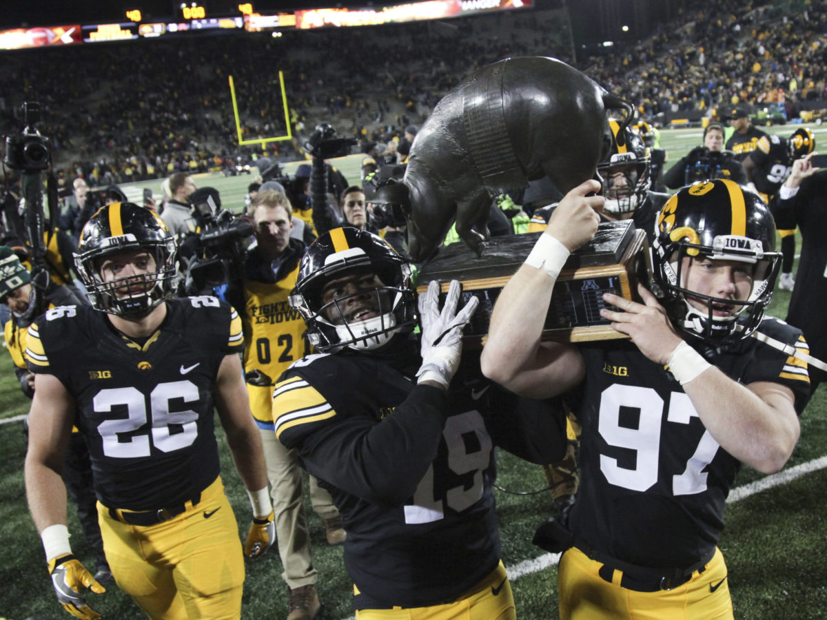 Iowa football players carry the Floyd of Rosedale Trophy.