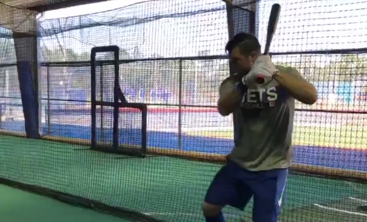 Tim Tebow swinging a bat in a cage.