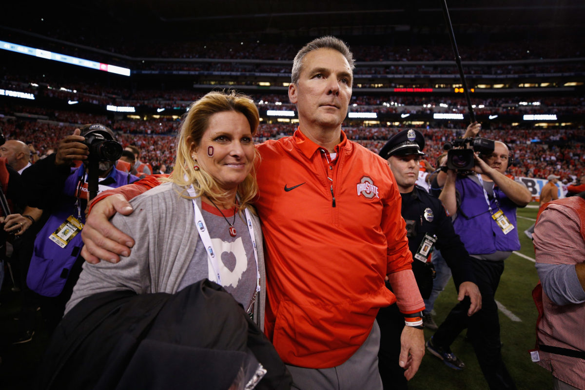 Urban Meyer walking off the field with his wife after an Ohio State game.