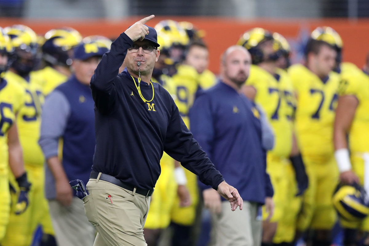 Head coach Jim Harbaugh of the Michigan Wolverines gathers his team before the start of the game.