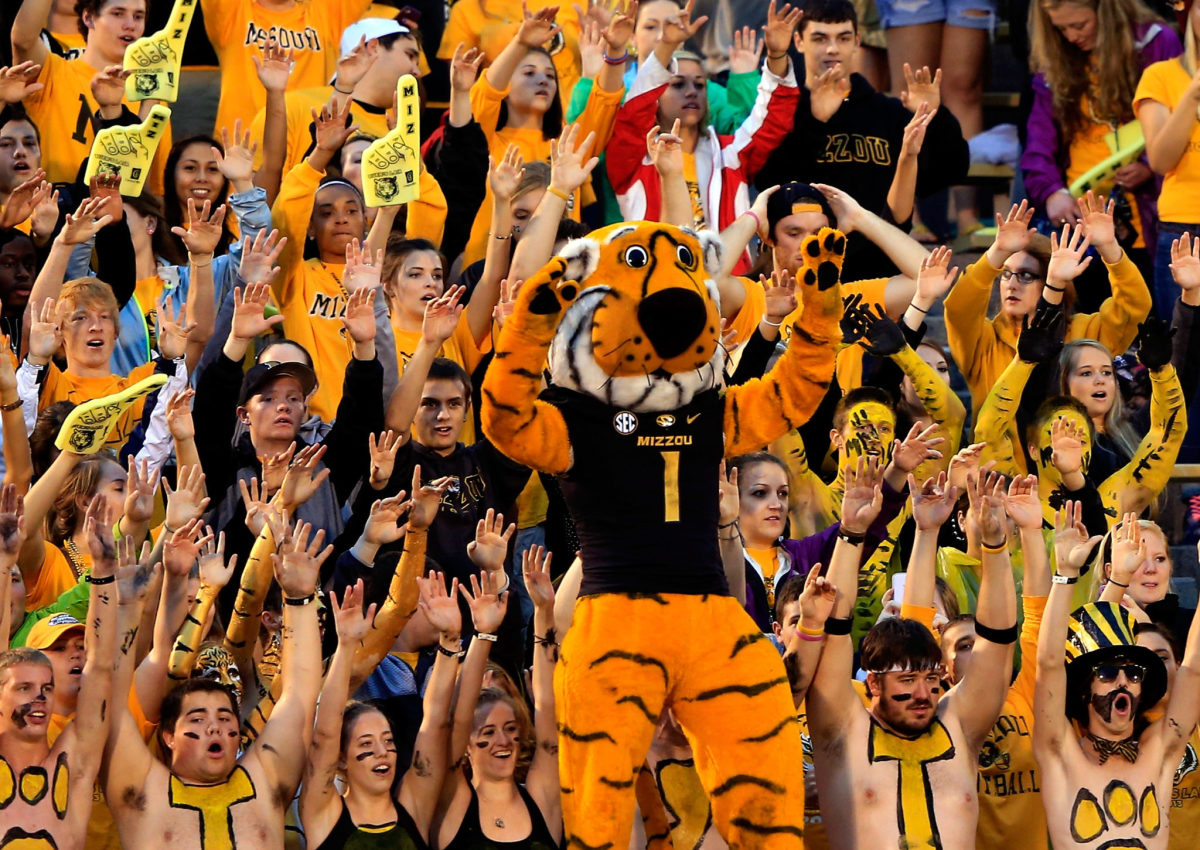 Missouri's mascot standing with the team's fans during a football game.