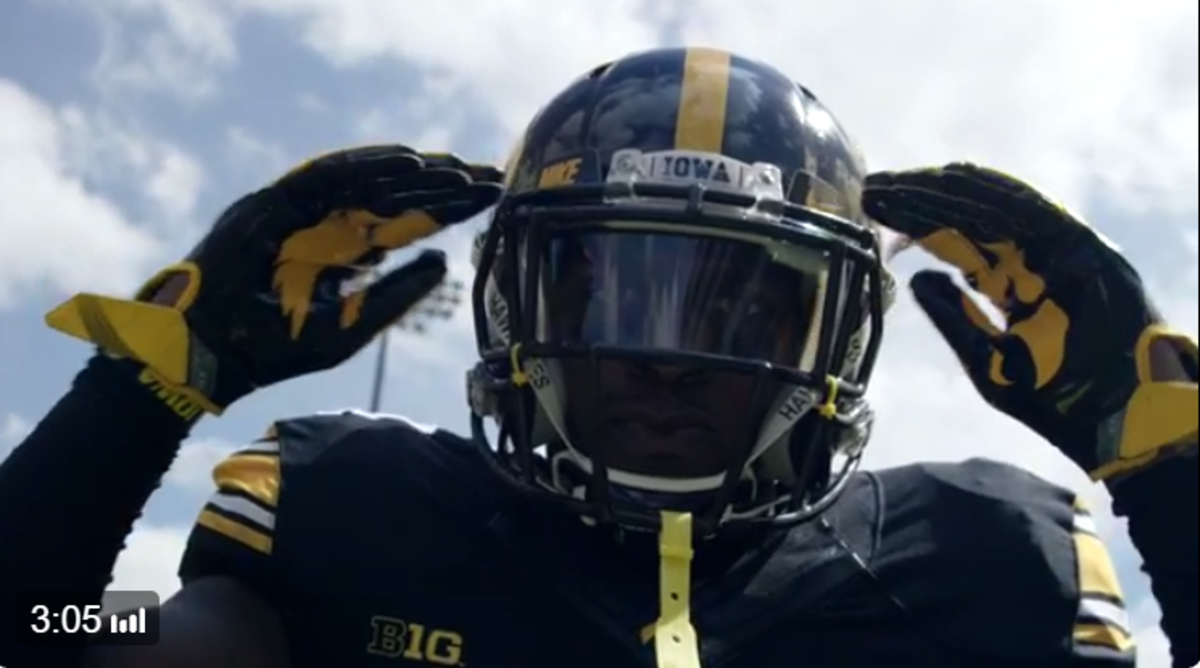 An Iowa football player touching his helmet.