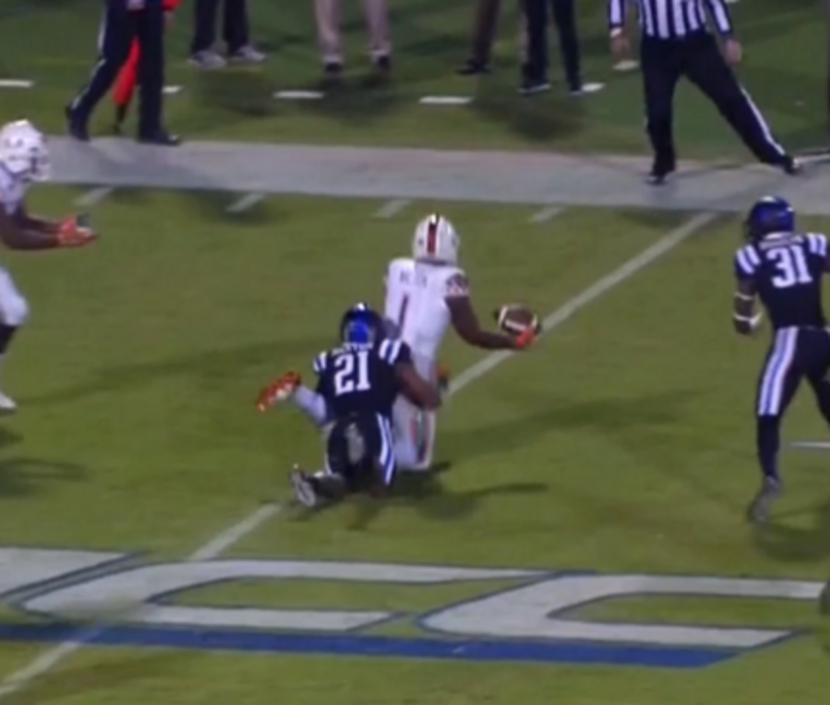 Miami football player gets tackled by a Duke defender.