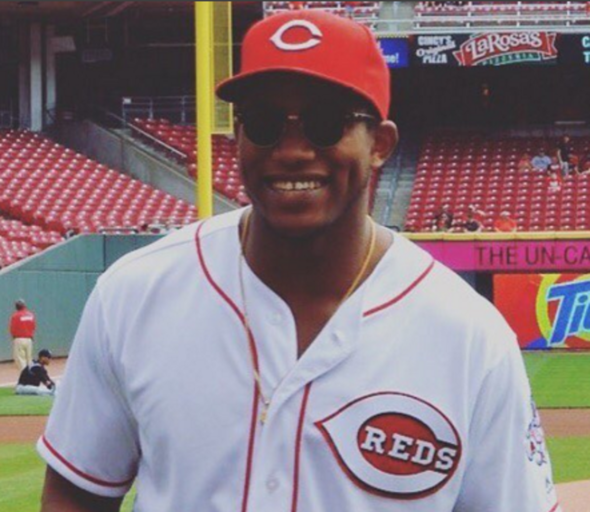 Darron Lee smiles in Cincinnati Reds hat and jersey before first pitch.