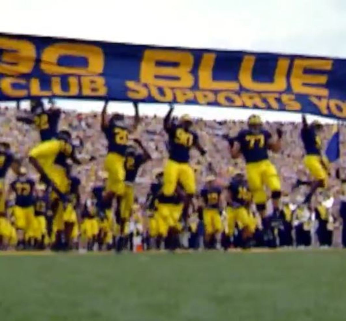 Michigan players run out under the GO Blue banner.