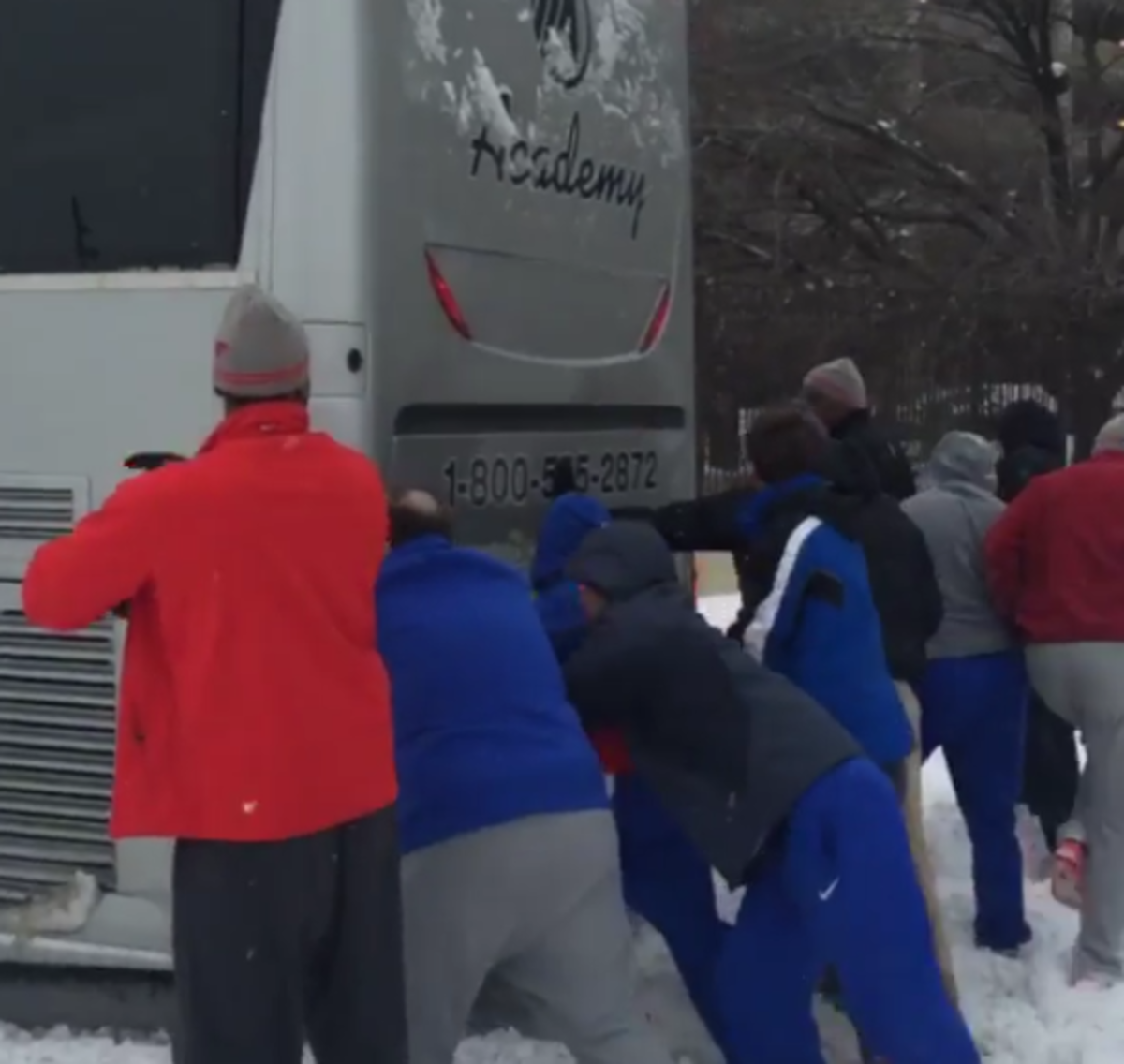 SMU players push bus after it gets stuck in snow.