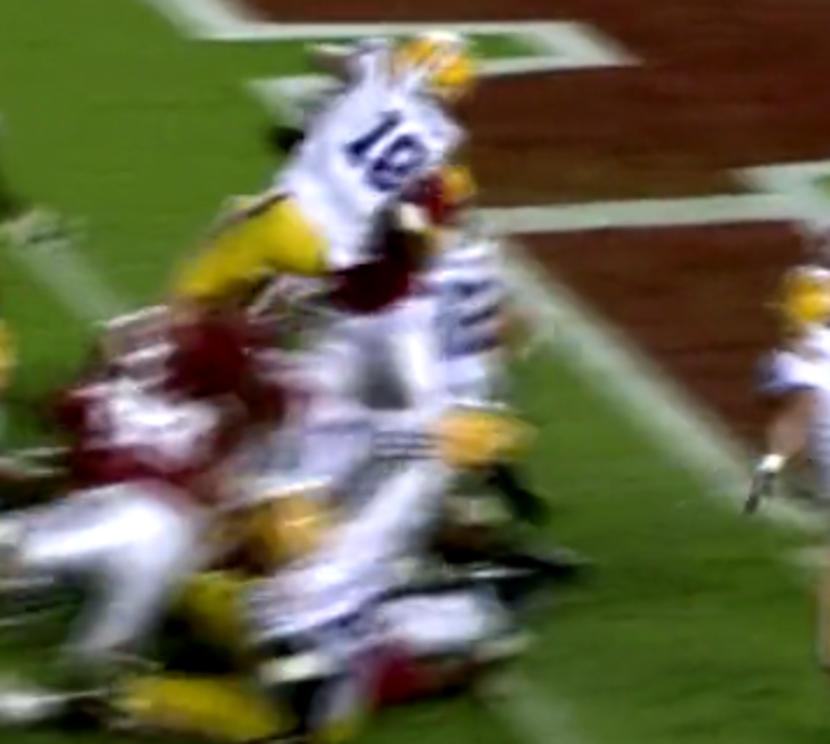 A LSU player jumps over the pile into the endzone.