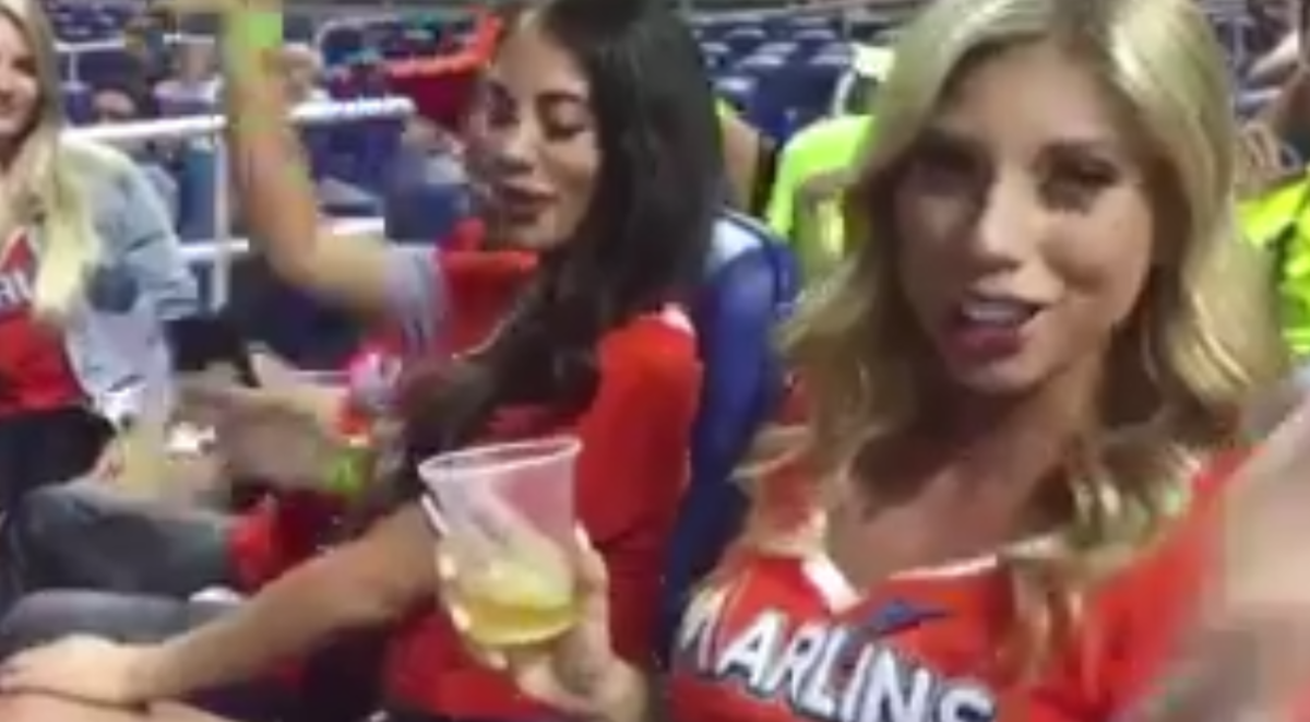 A woman drinks beer at a Marlins game.